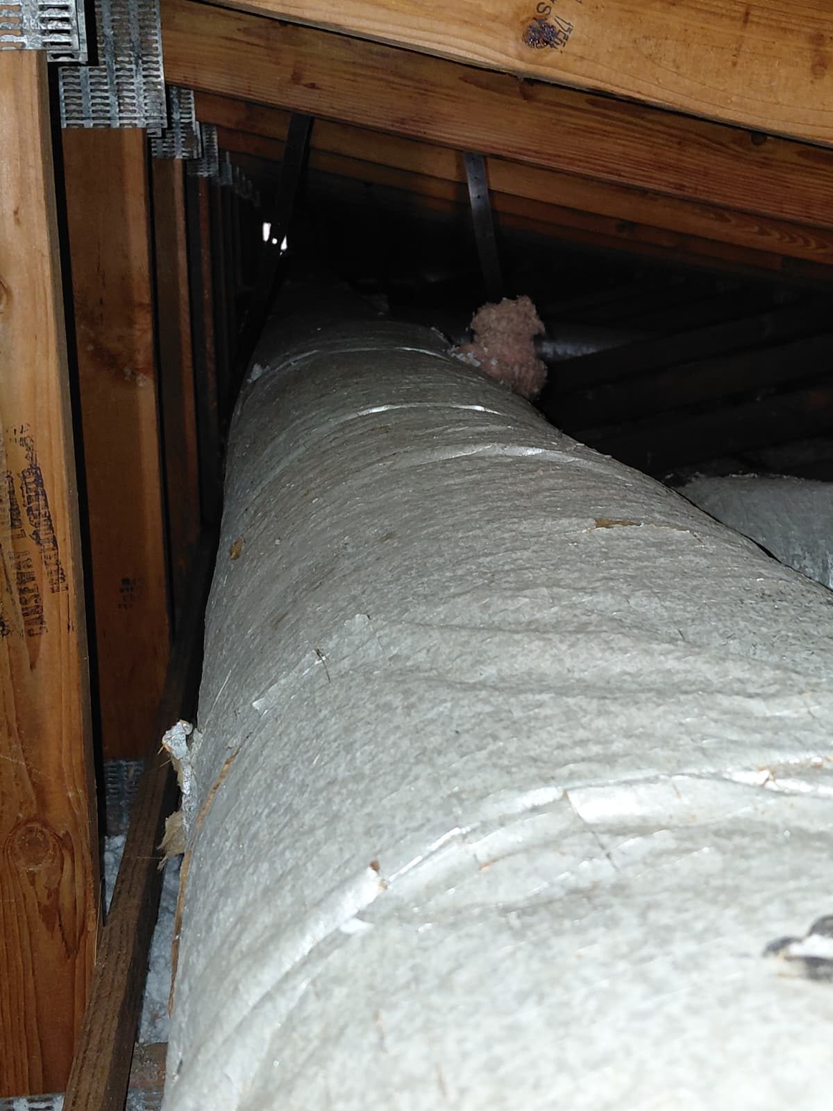 Small tears along the silver outer covering of an attic duct